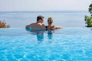 a man and a woman in a swimming pool in the water at Madrigale Panoramic&Lifestyle Hotel in Costermano