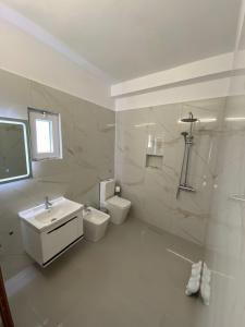 Un baño blanco con lavabo e inodoro. en Hotel Kaloshi, en Tirana