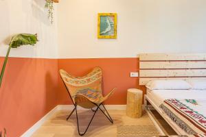 1 dormitorio con paredes de color naranja y silla junto a la cama en Bird House, en Barcelona