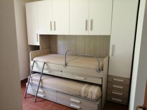 マリーナ・ディ・グロッセートにあるResidence LA CANOVAの白いキャビネット付きの客室の二段ベッド1台分です。