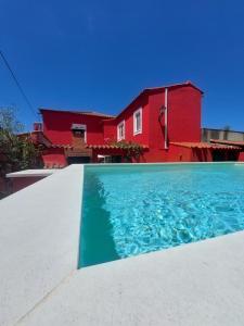 a house with a swimming pool in front of a red house at Sotam Country House in Góis