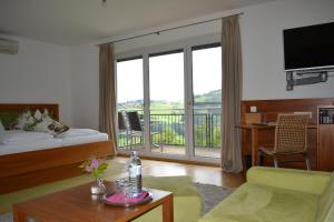 sala de estar con cama y balcón en Hotel Villa Rosa en Gamlitz