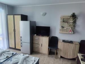 a room with a refrigerator and a desk with a television at Park and pool Studio Apostolovi in Nesebar