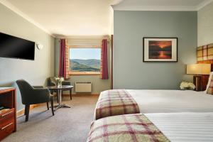 a hotel room with a bed and a desk and a window at Clan Macduff Hotel in Fort William