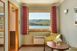 a room with a window and a chair and a table at Clan Macduff Hotel in Fort William