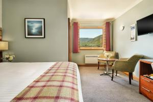 a hotel room with a bed and a desk and a window at Clan Macduff Hotel in Fort William