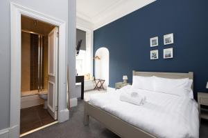 - une chambre avec des murs bleus et un grand lit blanc dans l'établissement ALTIDO Haymarket, à Édimbourg