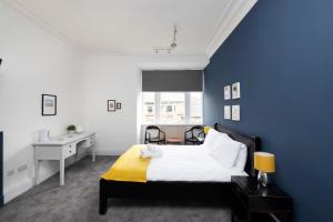 Dormitorio azul con cama y escritorio en ALTIDO Haymarket, en Edimburgo
