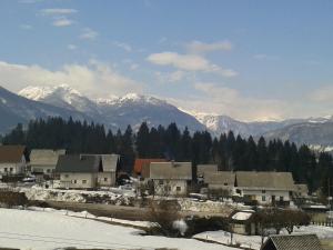 een stad in de sneeuw met besneeuwde bergen bij Apartments Bor in Bohinj