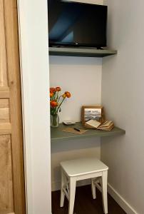 una piccola scrivania con sgabello e una TV a parete di Les Petits Volets 2 a Antibes