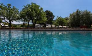 uma grande piscina de água com árvores e cadeiras em Country Relais La Mortella em Porto Ercole