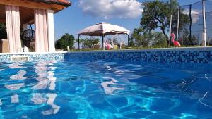 a blue swimming pool with an umbrella and an umbrella at House vacation with pool,near Šibenik in Planjane