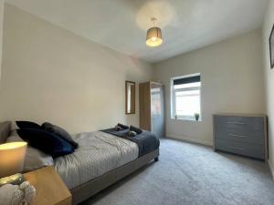 a bedroom with a bed and a dresser and a window at Western House - By Sigma Stays in Crewe