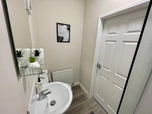a white bathroom with a sink and a mirror at Western House - By Sigma Stays in Crewe +8 photos