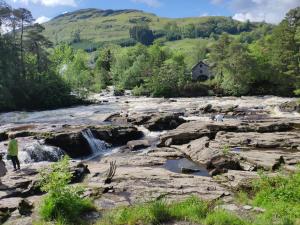 a person walking along a river with a waterfall at Craiglea Thistle in Killin