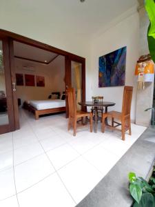 een woonkamer met een tafel en stoelen en een bed bij Soca Garden Guest house in Ubud