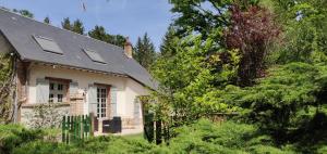 una casa antigua con techo negro y árboles en La Renardie, en La Ferté-Imbault