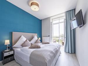 een slaapkamer met een bed met blauwe muren en een televisie bij Sonnenblume in der Seefahrtschule in Wustrow