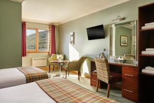a hotel room with two beds and a television at Clan Macduff Hotel in Fort William