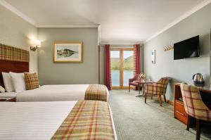 a hotel room with two beds and a television at Clan Macduff Hotel in Fort William