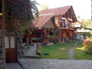 a log cabin with a porch and a building at Pensiunea Marin in Rona de Jos