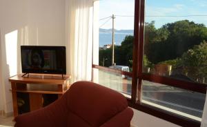 een woonkamer met een televisie en een groot raam bij Raxó con piscina en la urbanización in Raxo