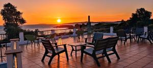 d'une terrasse avec des chaises et des tables et un coucher de soleil en arrière-plan. dans l'établissement Hotel Estrella del Mar, à A Lanzada