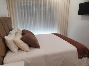 une chambre avec un lit avec des oreillers et une fenêtre dans l'établissement PIMENTA FOUR HOUSE, à Amarante