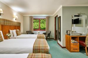 a hotel room with two beds and a television at Clan Macduff Hotel in Fort William