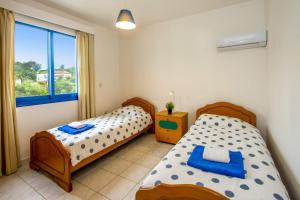 a bedroom with two beds and a window at Villa Galazio by Villa Plus in Argaka