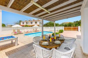un patio con mesa, sillas y piscina en Villa Haliki by Villa Plus, en Argaka