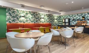 a restaurant with tables and white chairs and green wallpaper at Thon Hotel Astoria in Oslo
