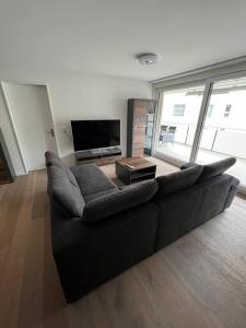 sala de estar con sofá negro y TV en Brand new apartment surrounded by Nature, en Schattdorf
