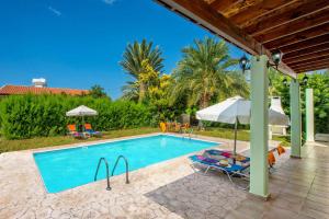 einen Pool mit einem Sonnenschirm und Stühlen sowie einem Tisch und einem Sonnenschirm in der Unterkunft Villa Iriss by Villa Plus in Polis Chrysochous
