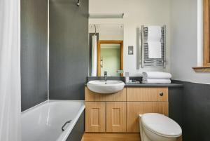 a bathroom with a tub and a sink and a toilet at Clan Macduff Hotel in Fort William