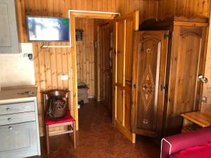 Pokój z drewnianymi ścianami, czerwonym krzesłem i drzwiami w obiekcie AMPIO MONOLOCALE IN CENTRO CHAMPOLUC w mieście Champoluc