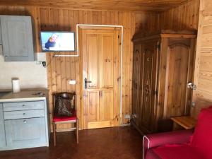 a kitchen with a red couch and a tv on the wall at AMPIO MONOLOCALE IN CENTRO CHAMPOLUC in Champoluc