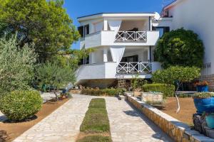 a white house with a walkway in front of it at Apartments Kosljun 123 in Košljun