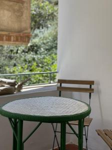 a green table and a bench in front of a window at Piso en la costa brava y al inicio del Pirineo in Portbou