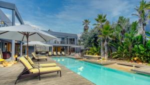 a pool with chairs and umbrellas next to a building at SOUL Atlantic Palms in Cape Town