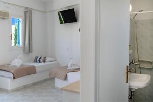 ein weißes Bad mit 2 Betten und einer Dusche in der Unterkunft Ayeri Hotel in Parikia