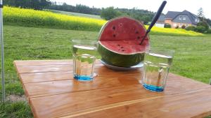 una sandía sentada en una mesa con dos vasos de agua en Autark-Camp Gleis A., en Dürrhennersdorf