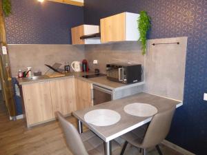 a kitchen with a table with chairs and a microwave at Le nid douillet d'Alsace et sa balnéo in Ottmarsheim