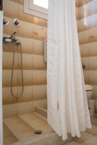 a shower with a white shower curtain in a bathroom at Maria's Apartments in Kavos