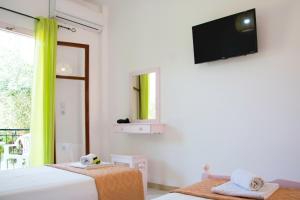 a bedroom with two beds and a television on the wall at Maria's Apartments in Kavos