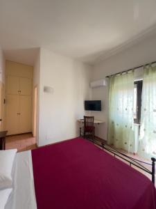 a bedroom with a large bed with a red blanket at Locanda Rosella in Giba