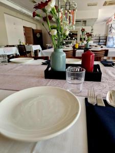 einen Tisch mit einer weißen Platte und einer Blumenvase in der Unterkunft Hotel Alpex View in Zabrze