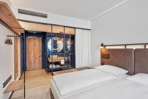 a bedroom with two beds and a glass wall at H2 Hotel Düsseldorf City in Düsseldorf