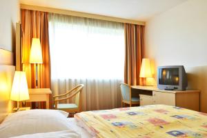 a hotel room with a bed and a television at Olympik Artemis in Prague