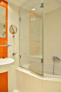a bathroom with a glass shower and a sink at Olympik Artemis in Prague